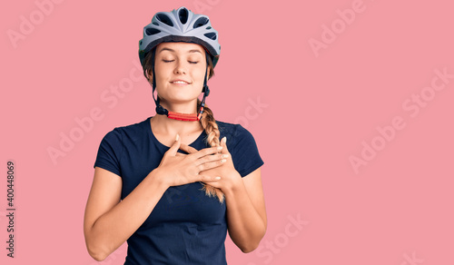 Beautiful caucasian woman wearing bike helmet smiling with hands on chest with closed eyes and grateful gesture on face. health concept.