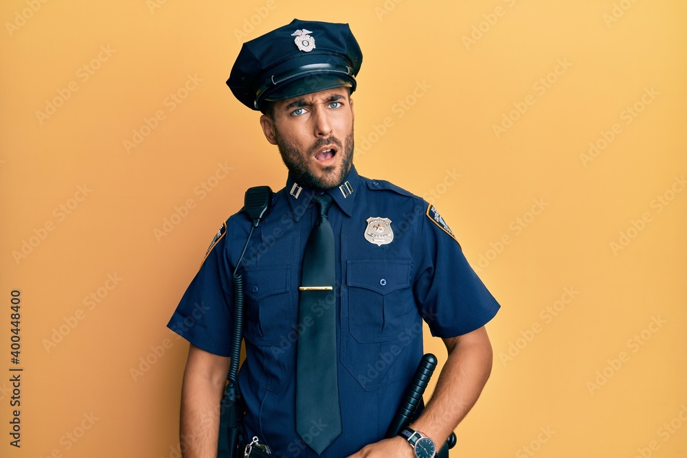 Handsome hispanic man wearing police uniform in shock face, looking skeptical and sarcastic, surprised with open mouth Handsome hispanic man wearing police uniform in shock face, looking skeptical and sarcastic, surprised with open mouth