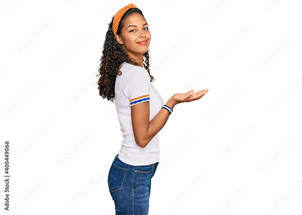 Young african american girl wearing casual clothes pointing aside with hands open palms showing copy space, presenting advertisement smiling excited happy Young african american girl wearing casual clothes pointing aside with hands open palms showing copy space, presenting advertisement smiling excited happy