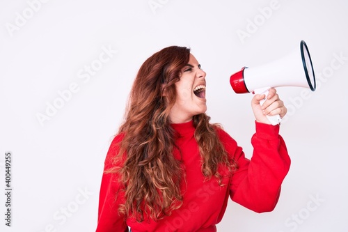 Young beautiful brunette woman screaming using megaphone over isolated white background