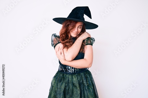 Young beautiful woman wearing witch halloween costume hugging oneself happy and positive, smiling confident. self love and self care © Krakenimages.com