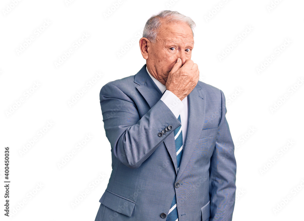 Senior handsome grey-haired man wearing elegant suit smelling something stinky and disgusting, intolerable smell, holding breath with fingers on nose. bad smell Senior handsome grey-haired man wearing elegant suit smelling something stinky and disgusting, intolerable smell, holding breath with fingers on nose. bad smell