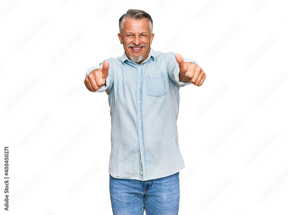 Middle age grey-haired man wearing casual clothes approving doing positive gesture with hand, thumbs up smiling and happy for success. winner gesture. Middle age grey-haired man wearing casual clothes approving doing positive gesture with hand, thumbs up smiling and happy for success. winner gesture.