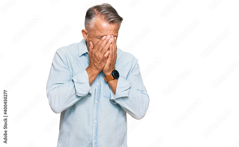 Middle age grey-haired man wearing casual clothes with sad expression covering face with hands while crying. depression concept. Middle age grey-haired man wearing casual clothes with sad expression covering face with hands while crying. depression concept.