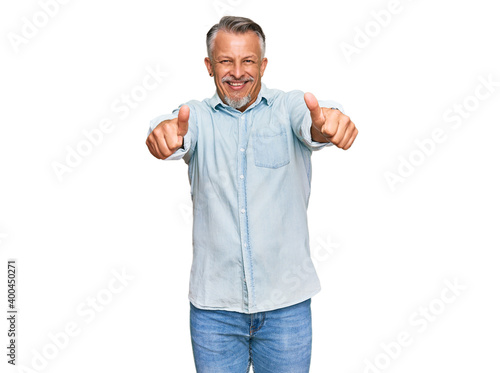 Middle age grey-haired man wearing casual clothes approving doing positive gesture with hand, thumbs up smiling and happy for success. winner gesture.