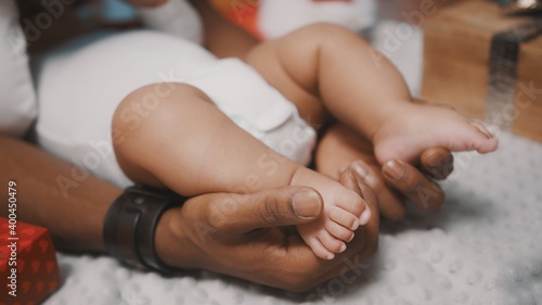 Close up, dad holding cute baby feet surrounded by christmas gifts. High quality photo