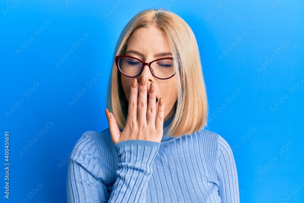 Young blonde woman wearing casual clothes and glasses bored yawning tired covering mouth with hand. restless and sleepiness. Young blonde woman wearing casual clothes and glasses bored yawning tired covering mouth with hand. restless and sleepiness.