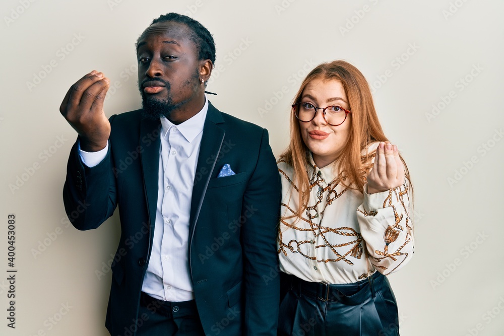 Young interracial couple wearing business and elegant clothes doing italian gesture with hand and fingers confident expression Young interracial couple wearing business and elegant clothes doing italian gesture with hand and fingers confident expression