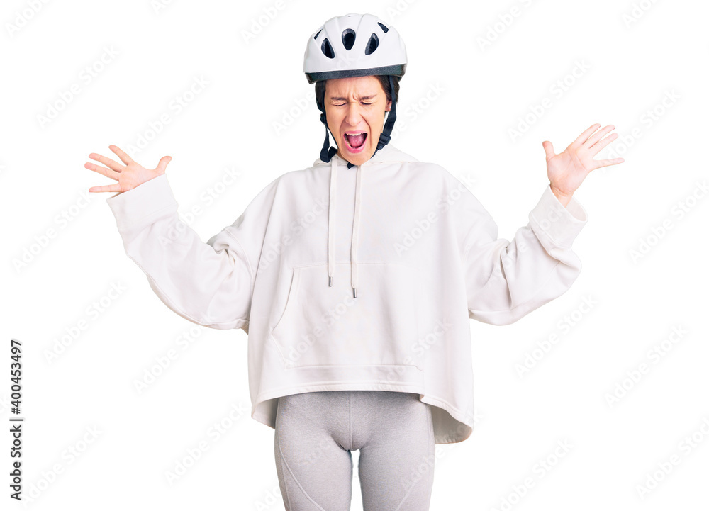 Beautiful brunette young woman wearing bike helmet and sporty clothes celebrating mad and crazy for success with arms raised and closed eyes screaming excited. winner concept Beautiful brunette young woman wearing bike helmet and sporty clothes celebrating mad and crazy for success with arms raised and closed eyes screaming excited. winner concept
