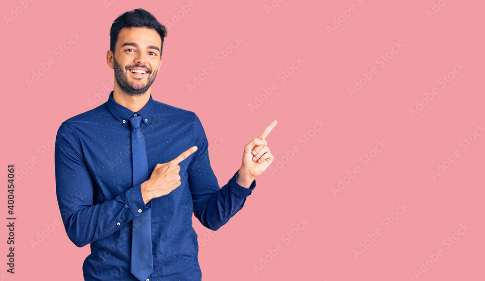 Young handsome hispanic man wearing business clothes smiling and looking at the camera pointing with two hands and fingers to the side. Young handsome hispanic man wearing business clothes smiling and looking at the camera pointing with two hands and fingers to the side.
