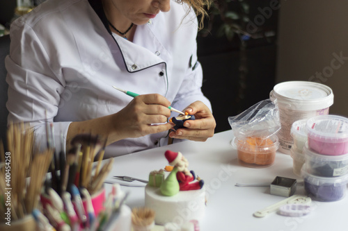 Cake decoration process. Baker uses the tools for sculpting fondant models.Edible art,cake designing and cake decorating. Selective focus model face.