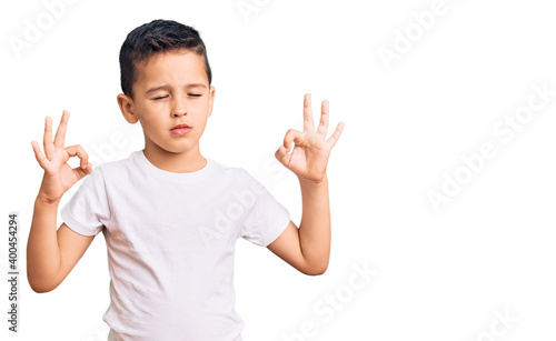 Little cute boy kid wearing casual white tshirt relax and smiling with eyes closed doing meditation gesture with fingers. yoga concept.