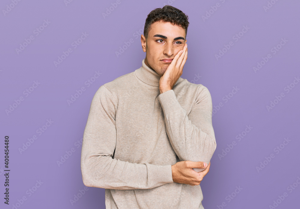 Hispanic young man wearing casual turtleneck sweater thinking looking tired and bored with depression problems with crossed arms. Hispanic young man wearing casual turtleneck sweater thinking looking tired and bored with depression problems with crossed arms.