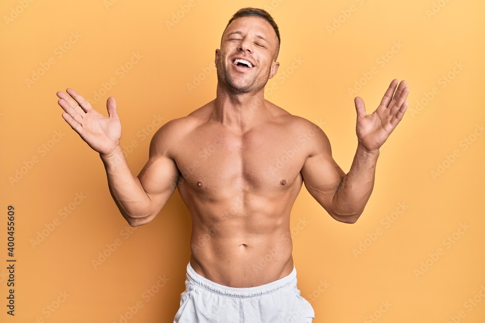 Handsome muscle man standing shirtless celebrating mad and crazy for