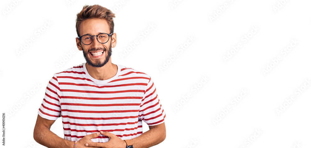 Handsome blond man with beard wearing casual clothes and glasses smiling and laughing hard out loud because funny crazy joke with hands on body. Handsome blond man with beard wearing casual clothes and glasses smiling and laughing hard out loud because funny crazy joke with hands on body.