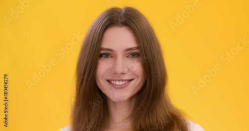 Cute playful woman winking to camera, flirting with you, yellow studio background