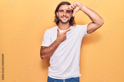 Young handsome man wearing casual clothes smiling making frame with hands and fingers with happy face. creativity and photography concept.