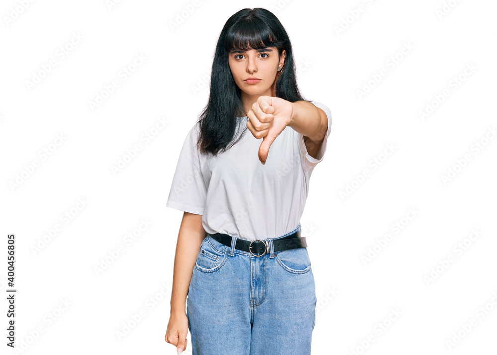 Young hispanic girl wearing casual clothes looking unhappy and angry showing rejection and negative with thumbs down gesture. bad expression. Young hispanic girl wearing casual clothes looking unhappy and angry showing rejection and negative with thumbs down gesture. bad expression.