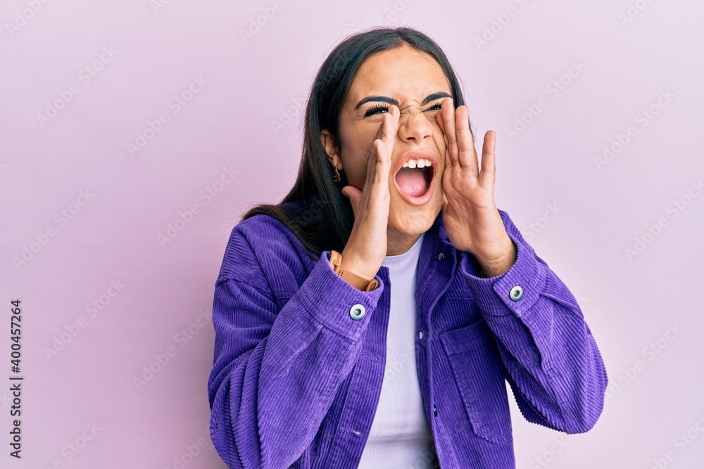 Young brunette woman wearing casual clothes shouting angry out loud with hands over mouth Young brunette woman wearing casual clothes shouting angry out loud with hands over mouth