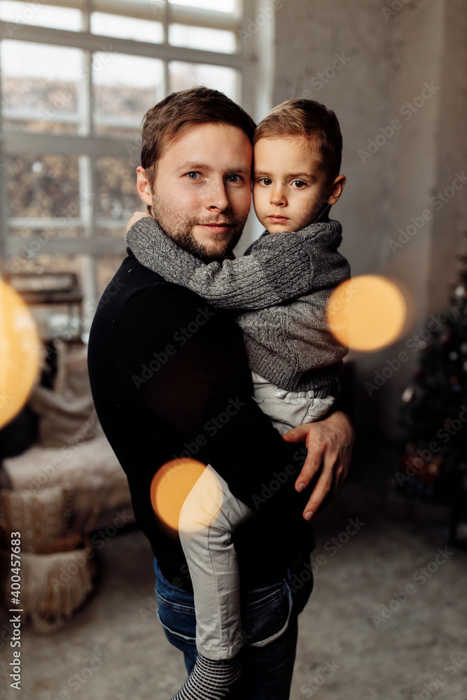 Portrait of handsome father hold little son in arms, cuddling and smiling. Caring parent with joyful kid celebrate winter holidays at home, enjoy happy moments, Christmas Eve concept Portrait of handsome father hold little son in arms, cuddling and smiling. Caring parent with joyful kid celebrate winter holidays at home, enjoy happy moments, Christmas Eve concept