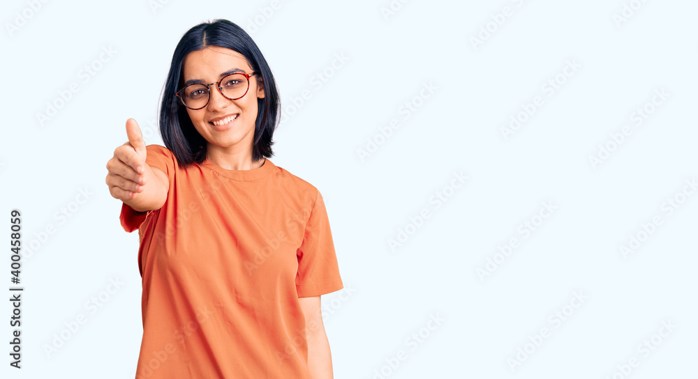 Young beautiful latin woman wearing casual clothes smiling friendly offering handshake as greeting and welcoming. successful business. Young beautiful latin woman wearing casual clothes smiling friendly offering handshake as greeting and welcoming. successful business.