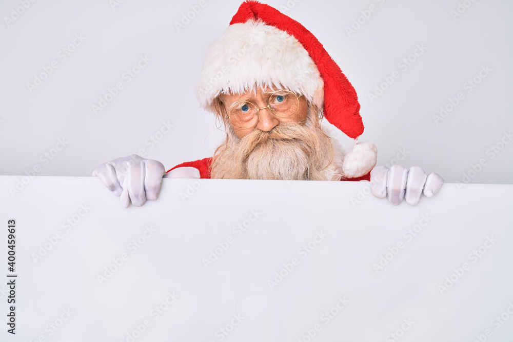 Naklejka premium Old senior man with grey hair and long beard wearing santa claus costume holding banner depressed and worry for distress, crying angry and afraid. sad expression.