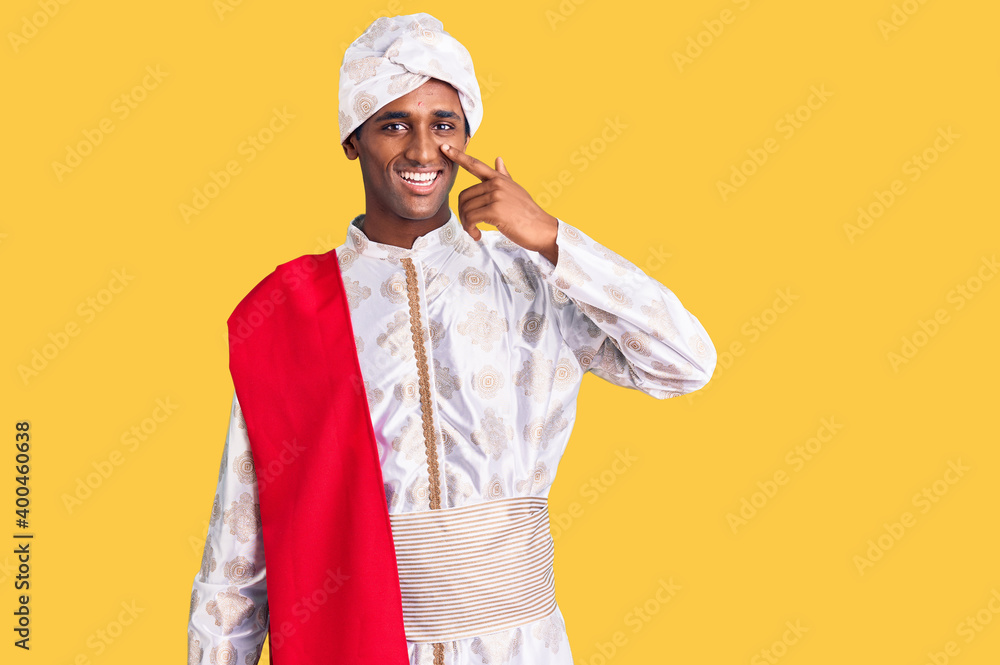 African handsome man wearing tradition sherwani saree clothes pointing with hand finger to face and nose, smiling cheerful. beauty concept African handsome man wearing tradition sherwani saree clothes pointing with hand finger to face and nose, smiling cheerful. beauty concept