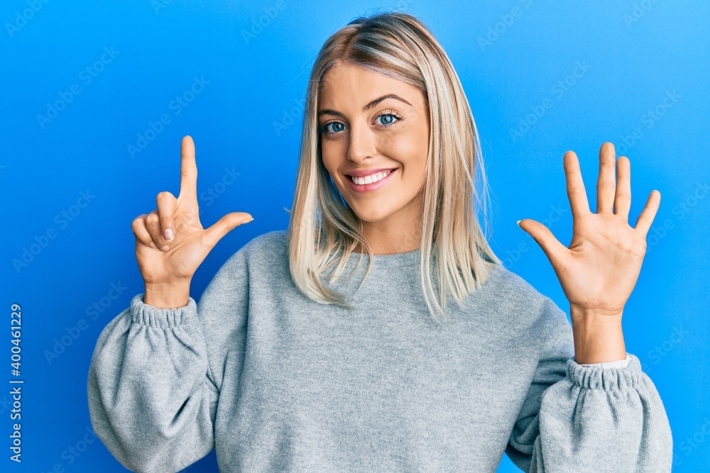 Beautiful blonde woman wearing casual clothes showing and pointing up with fingers number seven while smiling confident and happy. Beautiful blonde woman wearing casual clothes showing and pointing up with fingers number seven while smiling confident and happy.