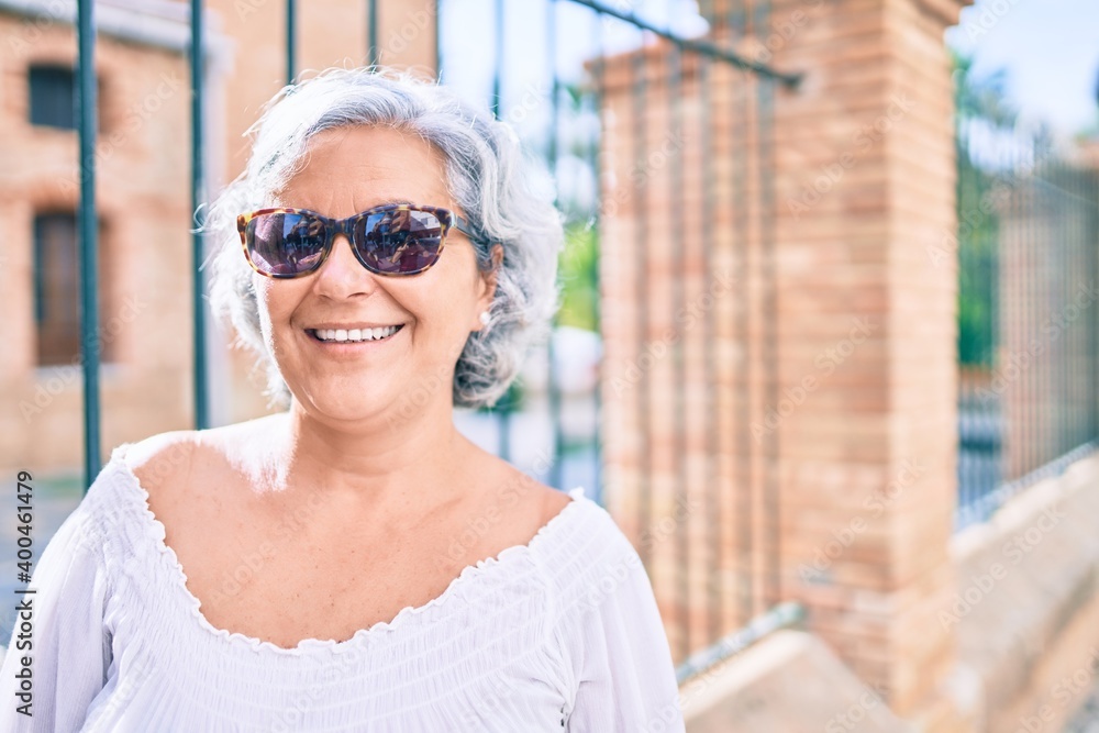 Middle age woman with grey hair smiling happy outdoors