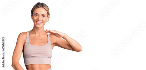 Beautiful caucasian woman wearing sportswear gesturing with hands showing big and large size sign, measure symbol. smiling looking at the camera. measuring concept.