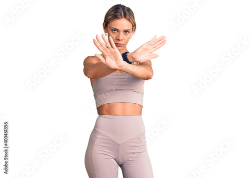 Fototapeta Naklejka Na Ścianę i Meble -  Beautiful caucasian woman wearing sportswear rejection expression crossing arms and palms doing negative sign, angry face