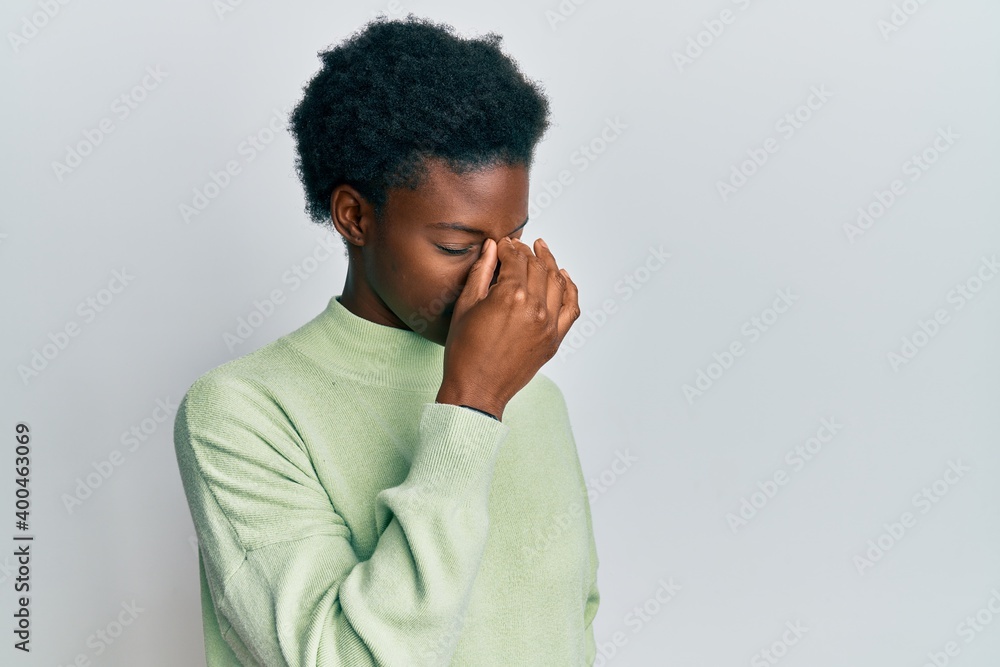 Young african american girl wearing casual clothes tired rubbing nose and eyes feeling fatigue and headache. stress and frustration concept. Young african american girl wearing casual clothes tired rubbing nose and eyes feeling fatigue and headache. stress and frustration concept.