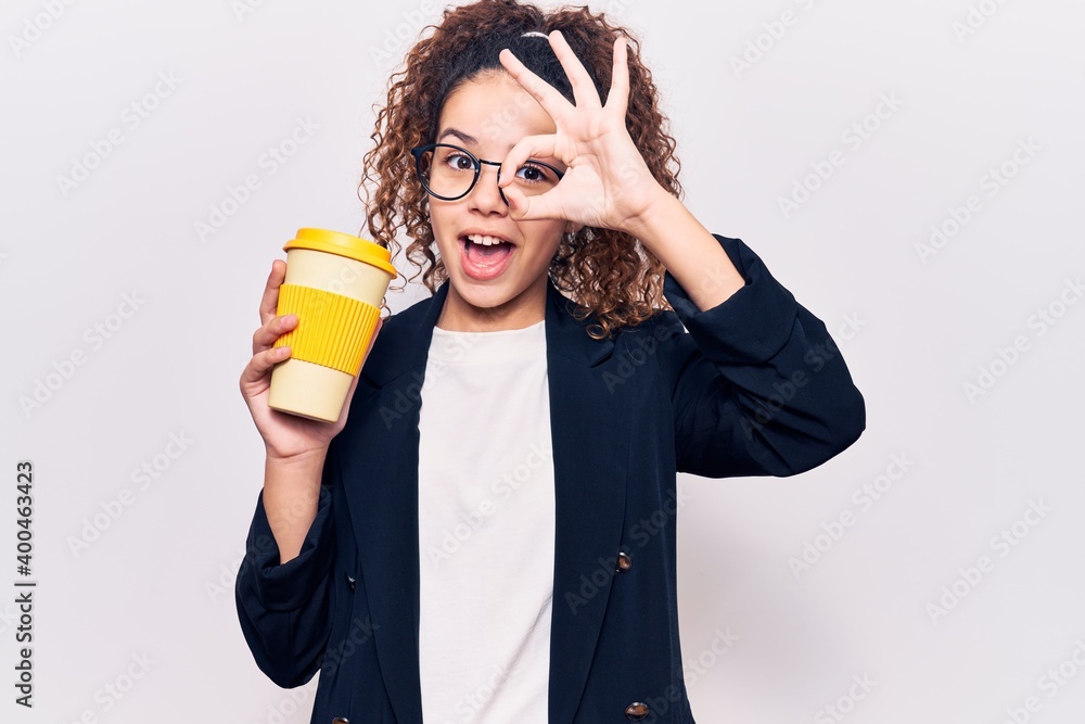 Beautiful kid girl with curly hair wearing business clothes and glasses holding takeaway cup of coffee smiling happy doing ok sign with hand on eye looking through fingers Beautiful kid girl with curly hair wearing business clothes and glasses holding takeaway cup of coffee smiling happy doing ok sign with hand on eye looking through fingers