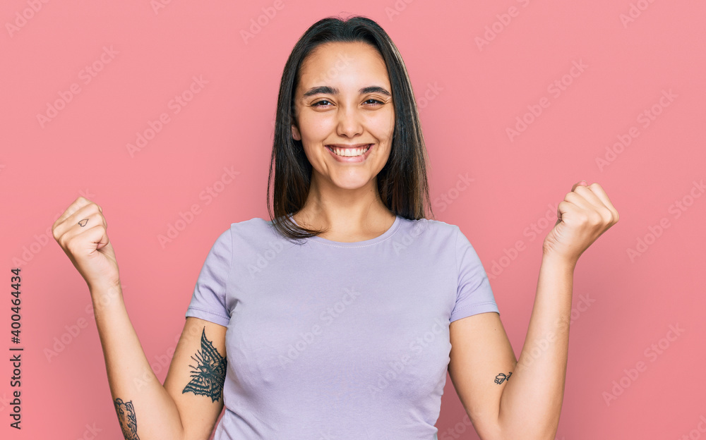 Young hispanic woman wearing casual clothes screaming proud, celebrating victory and success very excited with raised arms Young hispanic woman wearing casual clothes screaming proud, celebrating victory and success very excited with raised arms
