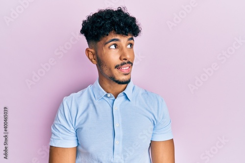 Young arab handsome man wearing casual clothes looking to side, relax profile pose with natural face and confident smile.