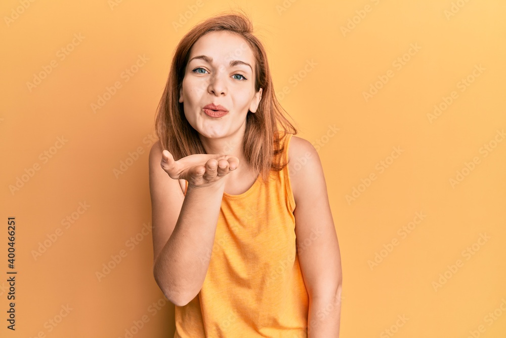 Young caucasian woman wearing casual style with sleeveless shirt looking at the camera blowing a kiss with hand on air being lovely and sexy. love expression.