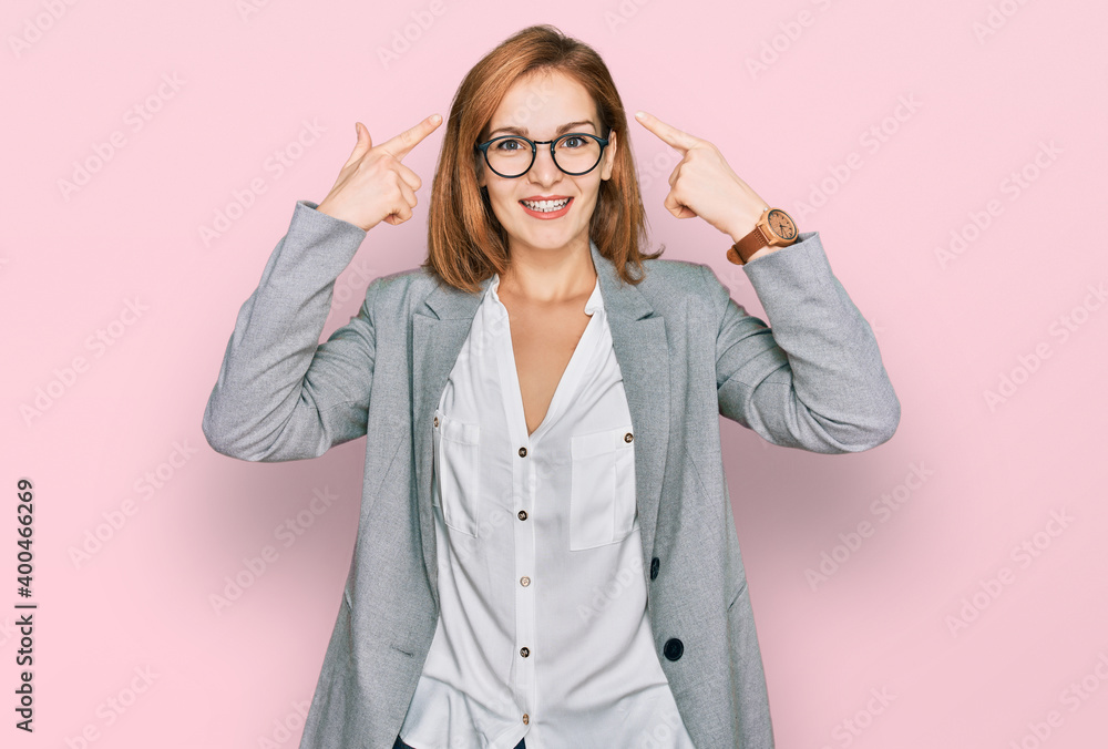 Young caucasian woman wearing business style and glasses smiling pointing to head with both hands finger, great idea or thought, good memory