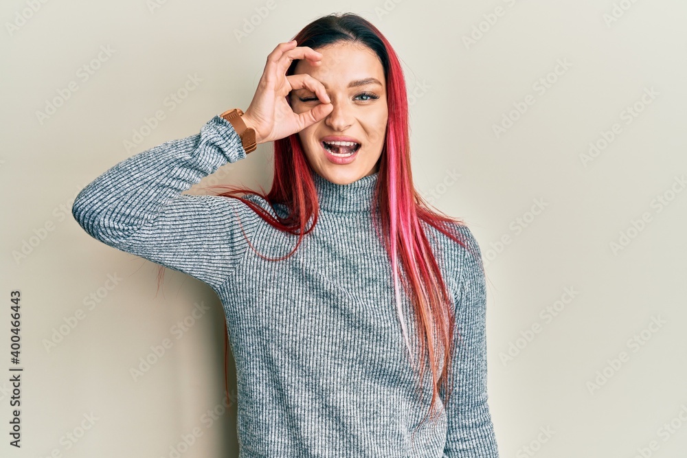 Young caucasian woman wearing casual clothes doing ok gesture with hand smiling, eye looking through fingers with happy face.