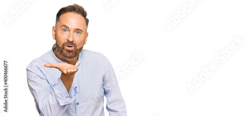 Handsome middle age man wearing business shirt looking at the camera blowing a kiss with hand on air being lovely and sexy. love expression.