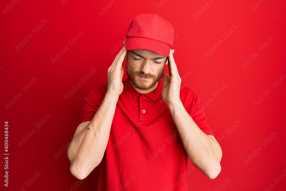 Young redhead man wearing delivery uniform and cap suffering from headache desperate and stressed because pain and migraine. hands on head. Young redhead man wearing delivery uniform and cap suffering from headache desperate and stressed because pain and migraine. hands on head.