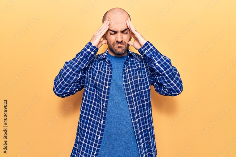 Young handsome bald man wearing casual shirt with hand on head, headache because stress. suffering migraine. Young handsome bald man wearing casual shirt with hand on head, headache because stress. suffering migraine.