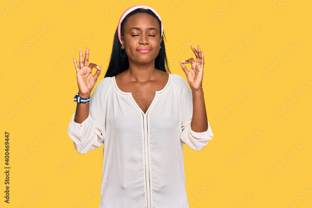 Young black woman wearing casual clothes relax and smiling with eyes closed doing meditation gesture with fingers. yoga concept. Young black woman wearing casual clothes relax and smiling with eyes closed doing meditation gesture with fingers. yoga concept.