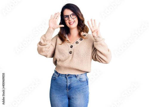 Beautiful young brunette woman wearing casual clothes and glasses showing and pointing up with fingers number nine while smiling confident and happy.