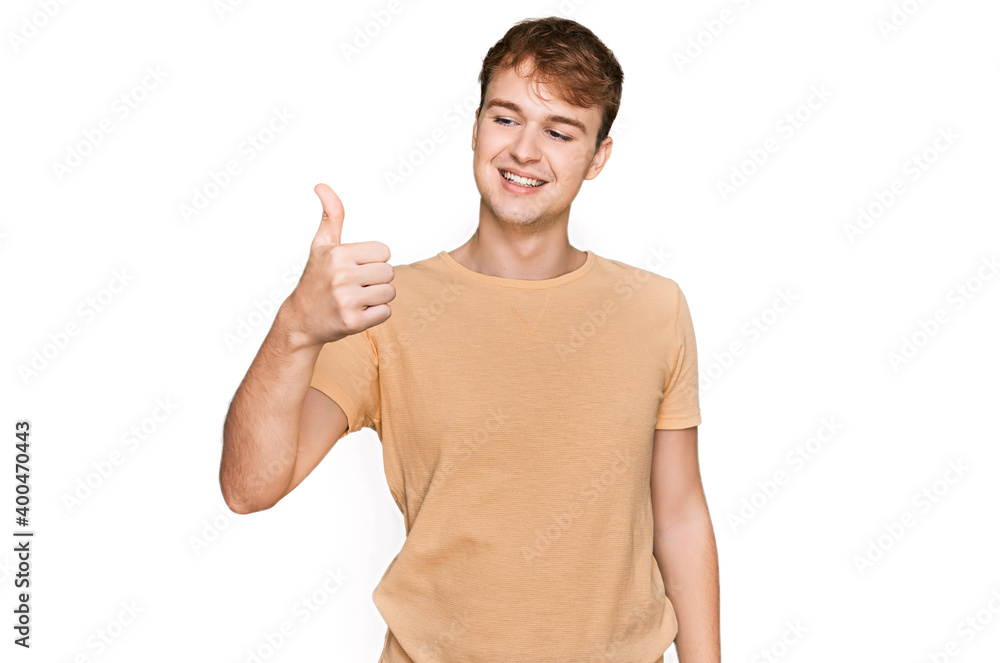 Young caucasian man wearing casual clothes looking proud, smiling doing thumbs up gesture to the side Young caucasian man wearing casual clothes looking proud, smiling doing thumbs up gesture to the side
