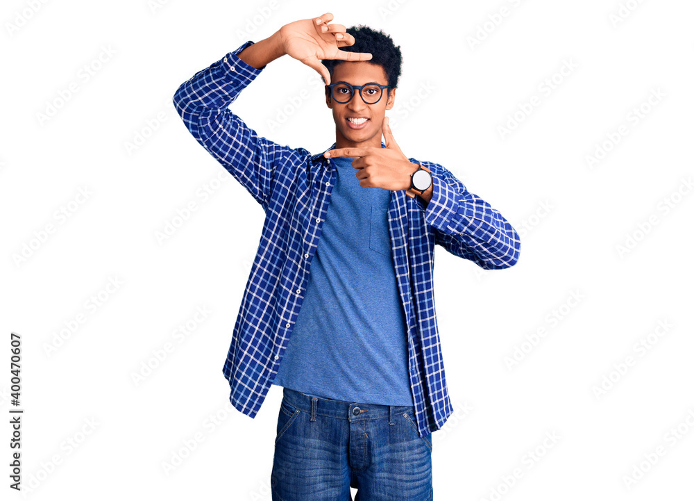 Young african american man wearing casual clothes and glasses smiling making frame with hands and fingers with happy face. creativity and photography concept. Young african american man wearing casual clothes and glasses smiling making frame with hands and fingers with happy face. creativity and photography concept.