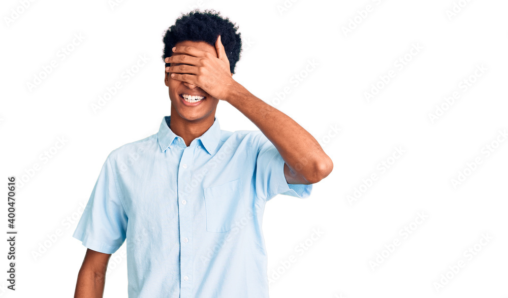 Young african american man wearing casual clothes smiling and laughing with hand on face covering eyes for surprise. blind concept. Young african american man wearing casual clothes smiling and laughing with hand on face covering eyes for surprise. blind concept.