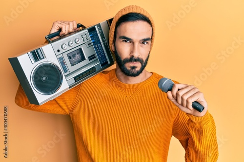 Young hispanic man holding boombox, listening to music singing with microphone skeptic and nervous, frowning upset because of problem. negative person.