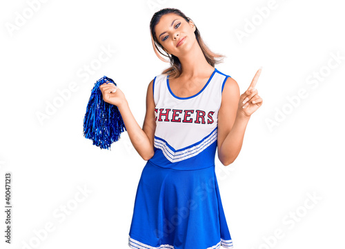 Young beautiful woman wearing cheerleader uniform pointing finger up with successful idea. exited and happy. number one.