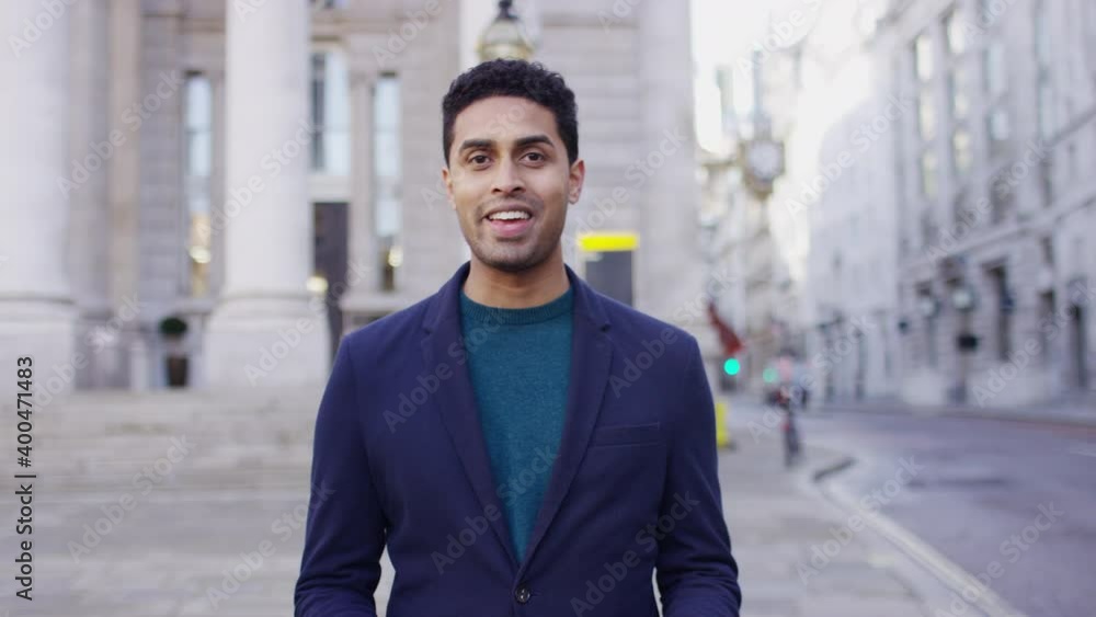 Young male presenter walking and talking towards camera in the city