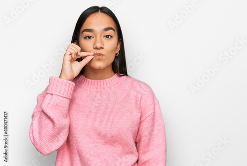 Young asian woman wearing casual winter sweater mouth and lips shut as zip with fingers. secret and silent, taboo talking